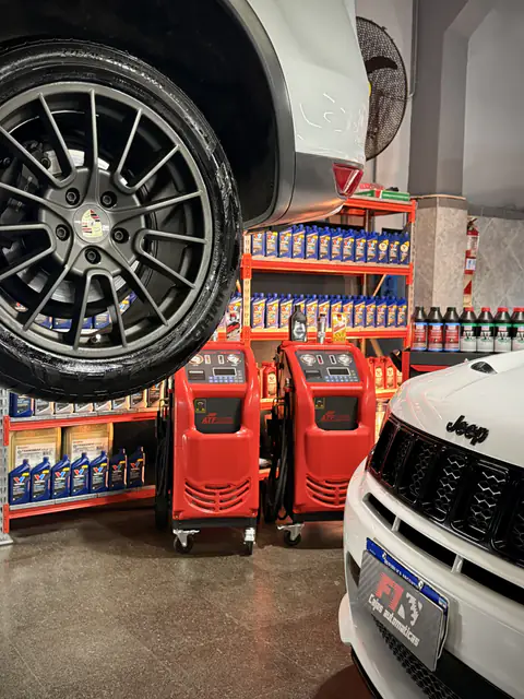 Dos equipos de diálisis ante estanterías de aceites, bajo la rueda de un Porsche elevado y junto a un Jeep