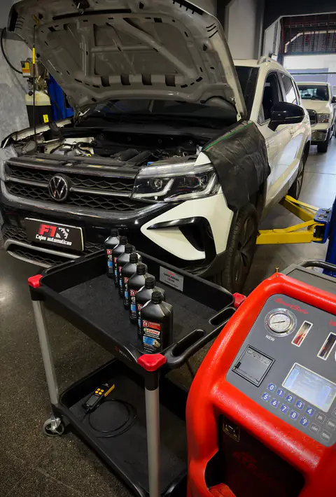 Camioneta Volkswagen blanca con capó abierto, carro con botellas Castrol y equipo de diálisis