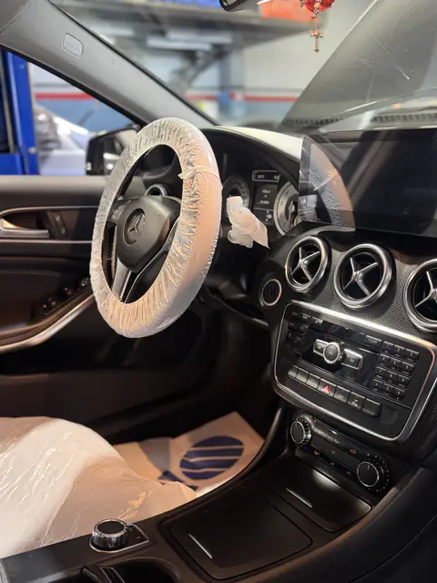 Interior de Mercedes-Benz con fundas protectoras en volante y asiento y cubrealfombra de papel