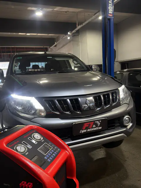 Pickup Mitsubishi gris con chapa F1 junto a la columna del elevador y el equipo de diálisis en primer plano