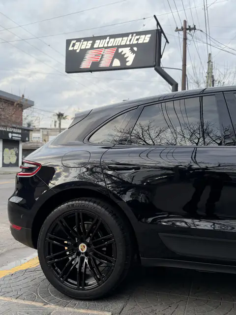 Porsche Macan negro de perfil trasero bajo el cartel de Cajas Automáticas F1