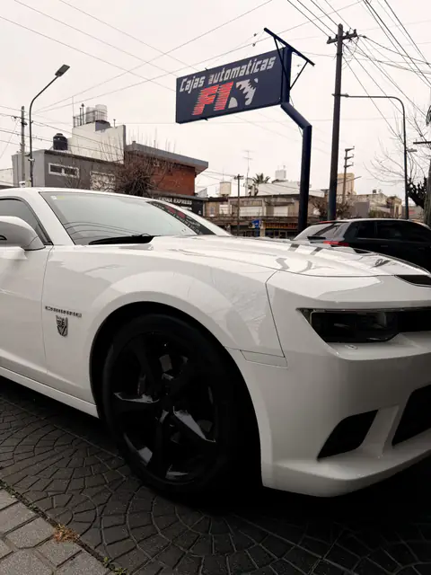 Chevrolet Camaro blanco con llantas negras, estacionado bajo el cartel de Cajas Automáticas F1