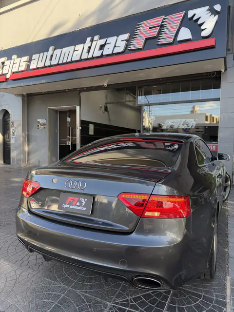 Audi RS5 gris visto desde atrás frente a la fachada de Cajas Automáticas F1