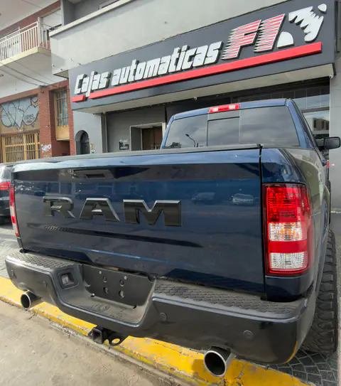 Pickup RAM azul oscuro vista desde atrás frente a la fachada de Cajas Automáticas F1