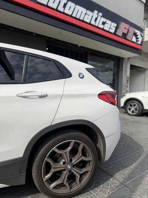 SUV BMW blanca de perfil, estacionada frente al local de Cajas Automáticas F1