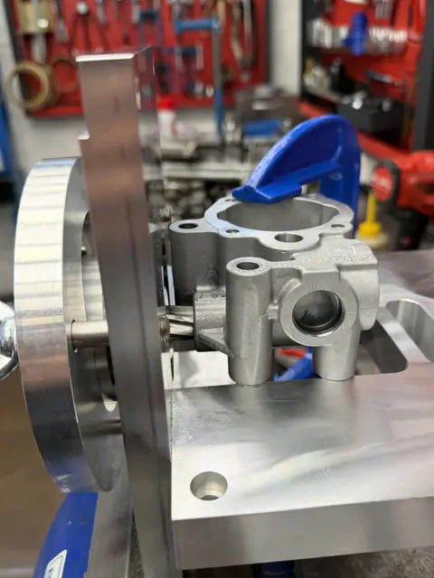 Pieza de aluminio en un dispositivo con volante, con una herramienta de corte entrando en uno de sus orificios