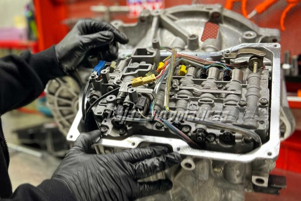 Técnico con guantes trabajando sobre el cuerpo de válvulas de una caja automática