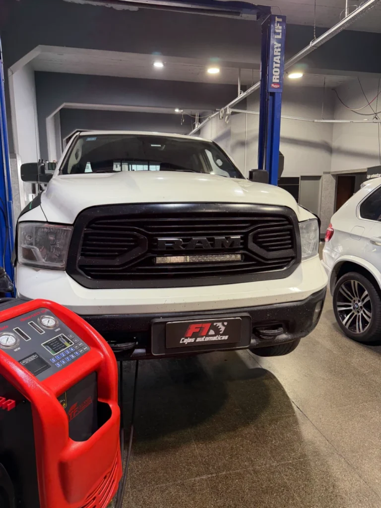 Pickup RAM blanca dentro del taller, junto a un equipo para el servicio de la transmisión