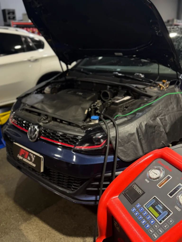 Volkswagen azul con el capó abierto, conectado a un equipo para el servicio de la transmisión