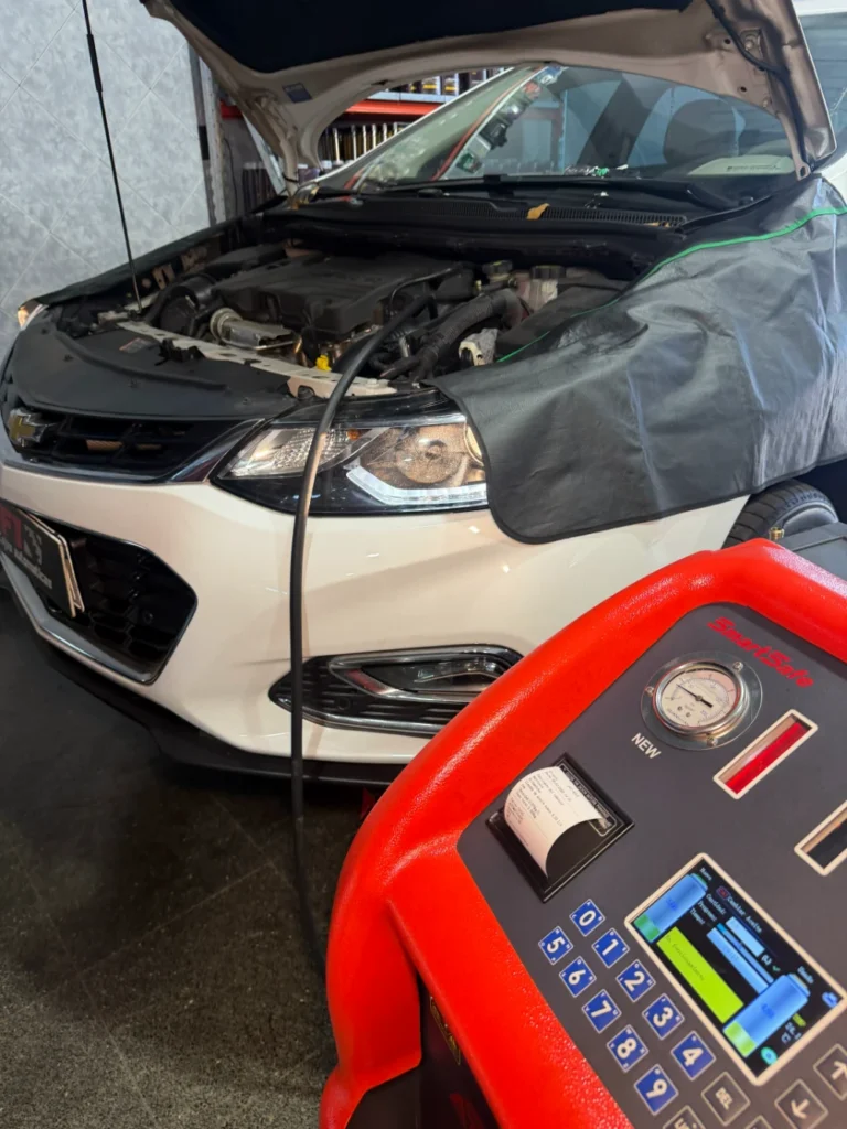 Auto blanco con el capó abierto y el equipo para el servicio de la transmisión en primer plano